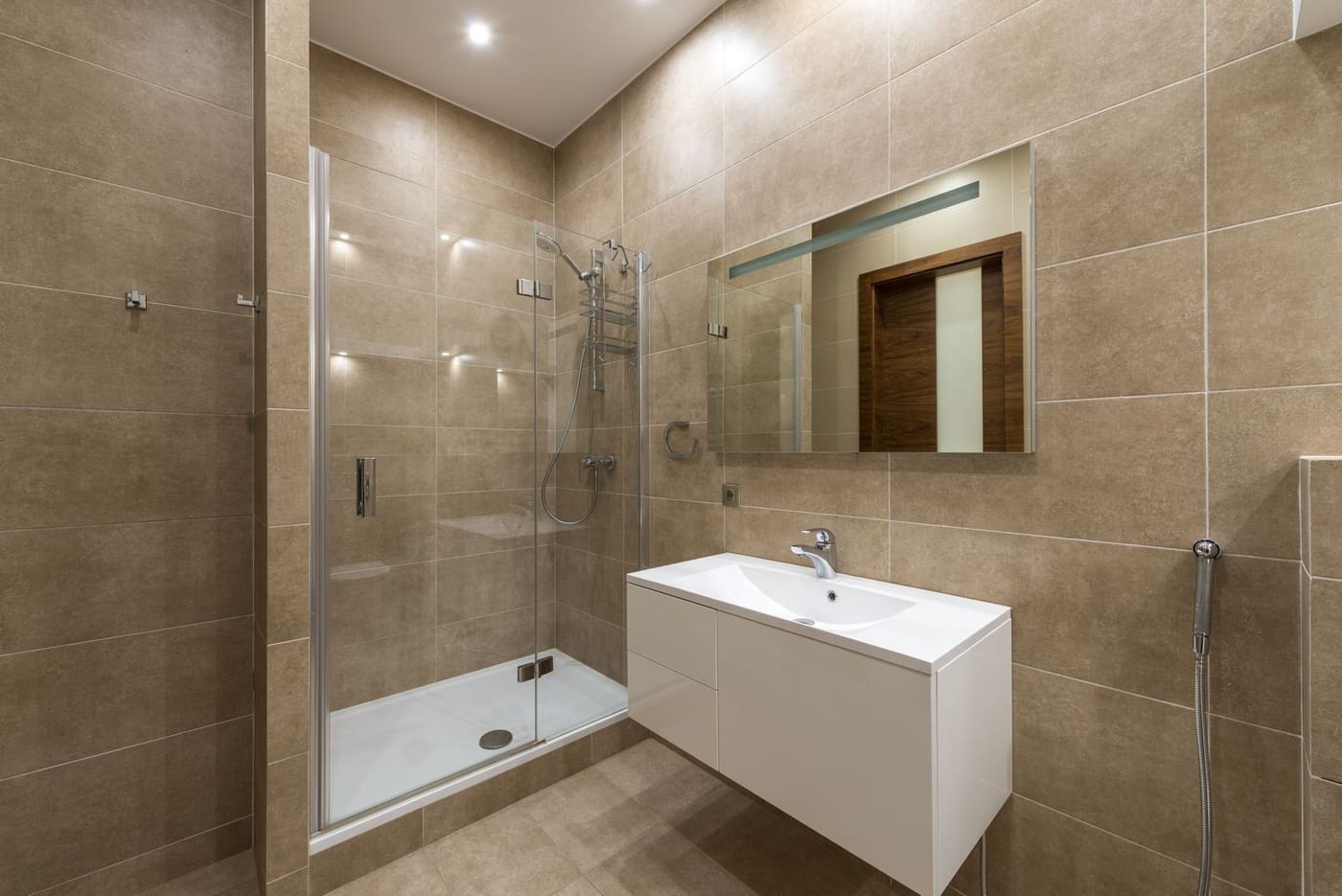 Bathroom with a tiled glass shower, a floating white vanity with a basin and a framed wall mirror