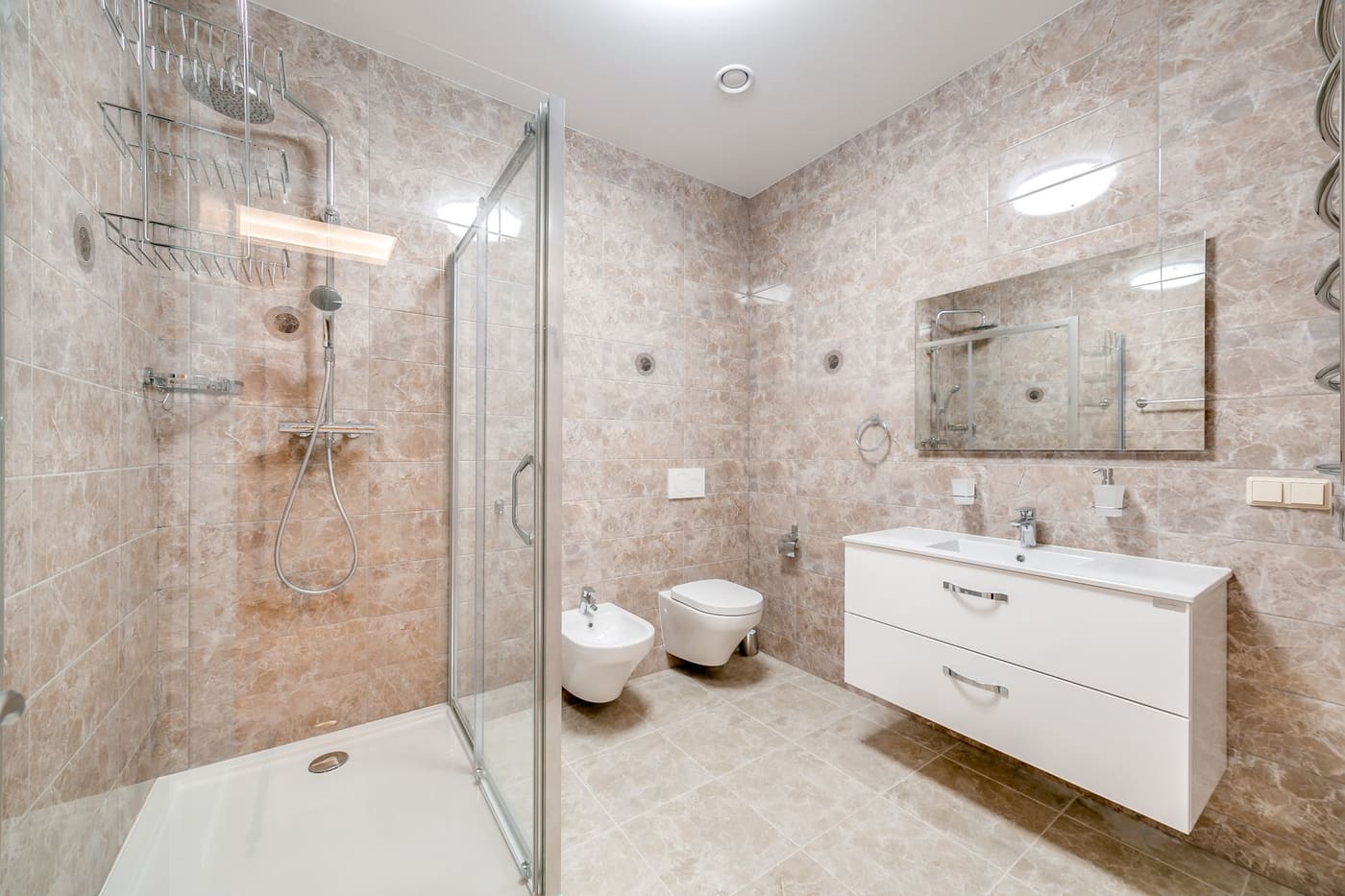 Bathroom with a wall-hung toilet beside a glass shower and a floating vanity with a mirror above