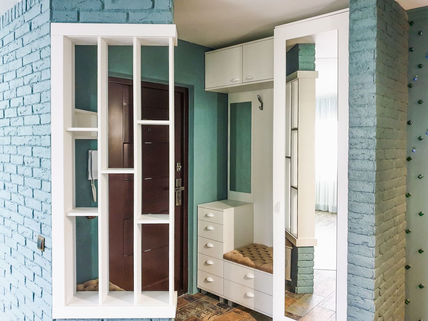 Narrow entryway with white shelving, a built-in bench and drawers beside a front door