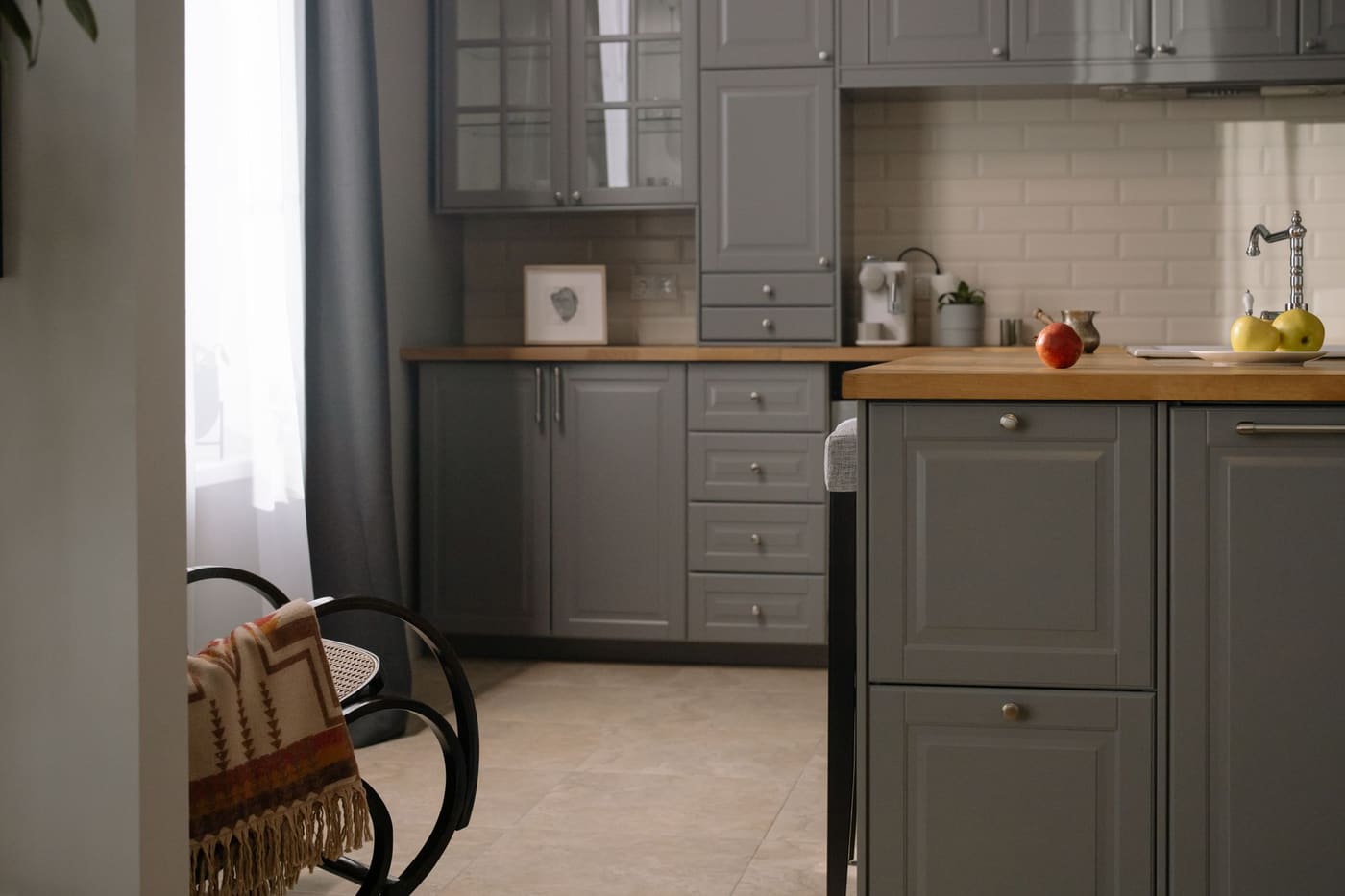 Gray kitchen cabinets with a wooden countertop and a window letting in daylight