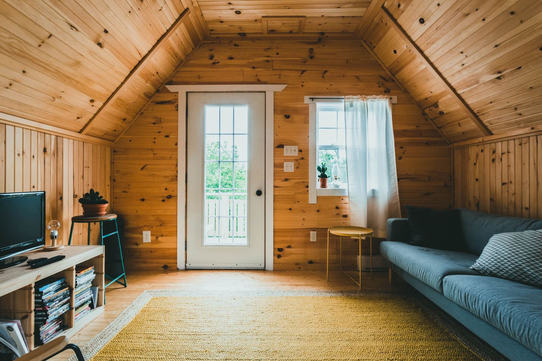 A bright wooden cabin interior with a sofa and a window
