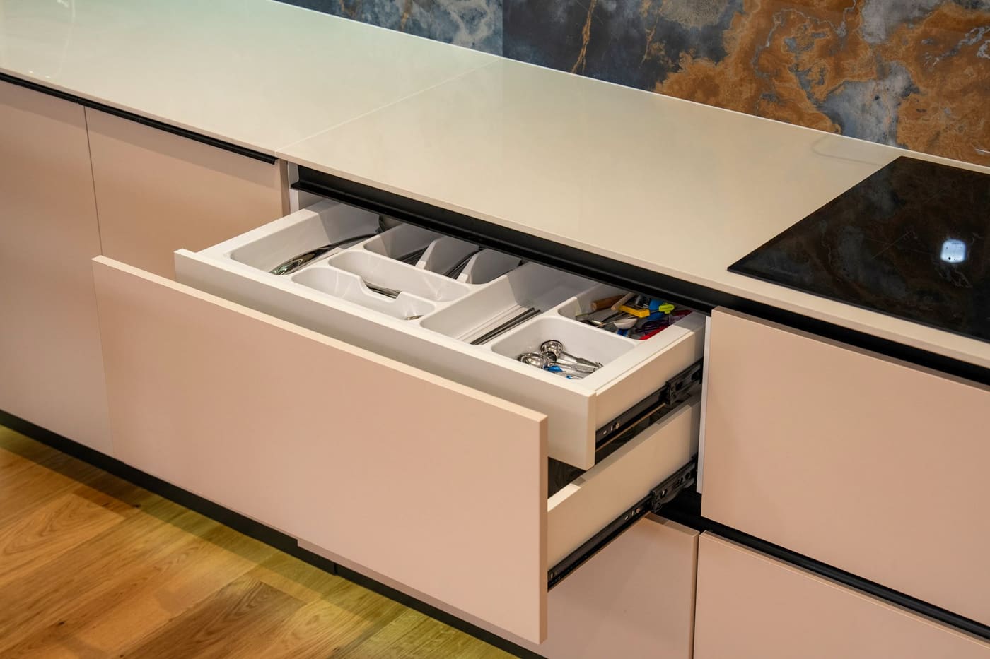 Open kitchen drawer with a divided tray holding a whisk, spatulas and other utensils