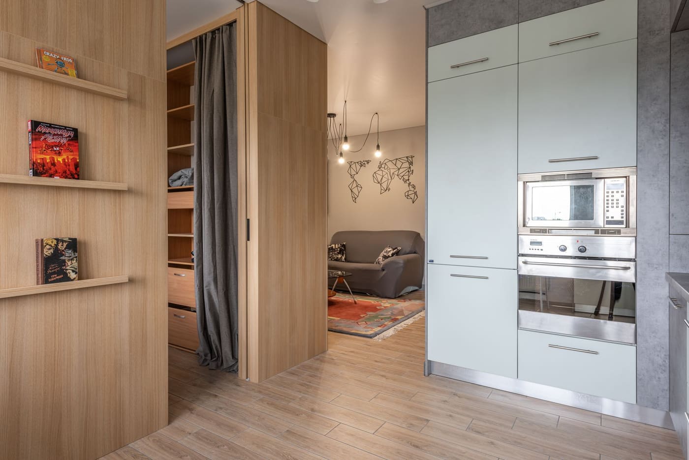 Open wooden shelving beside a doorway with a curtain, separating a kitchen area from a living room