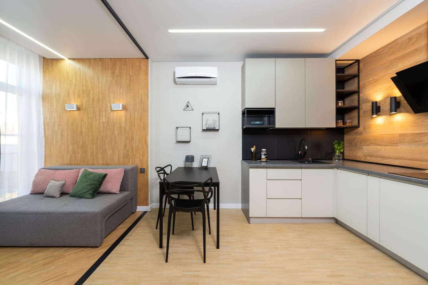 Light studio room with a sofa under a window and a small table, with open floor between them